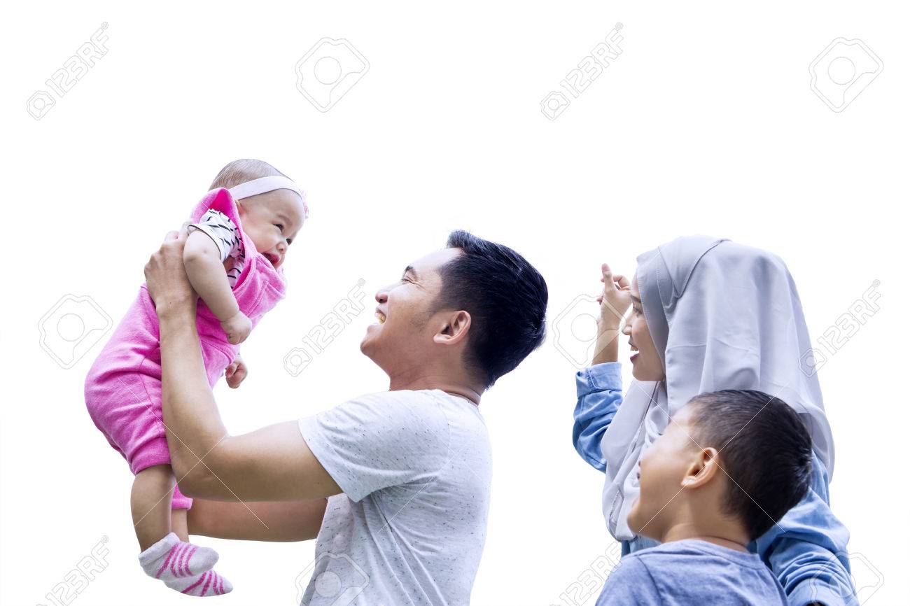 Keluarga muslim gembira sedang bermain dengan bayi di latar belakang putih.
