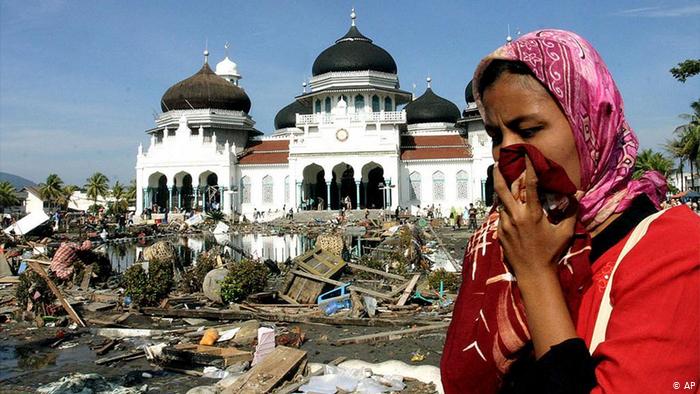 Gambar ombak besar tsunami membadai pantai dan memusnahkan bangunan.