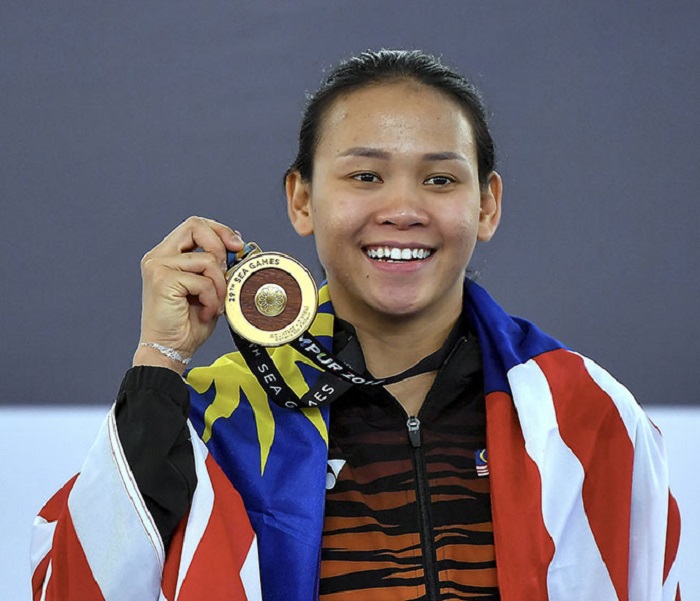 Gambar Pandelela Rinong, atlet terjun wanita Malaysia berdiri dengan pingat.