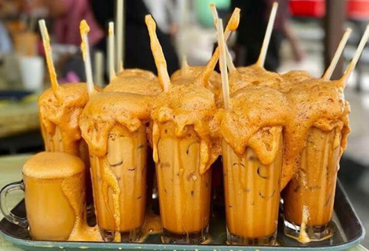 Segelas air teh ais sejuk yang menyegarkan diletakkan di atas meja kayu.