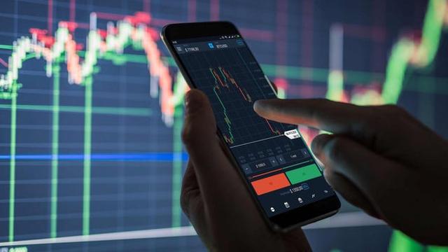 Lelaki memantau turun naik graf harga saham di skrin komputer.