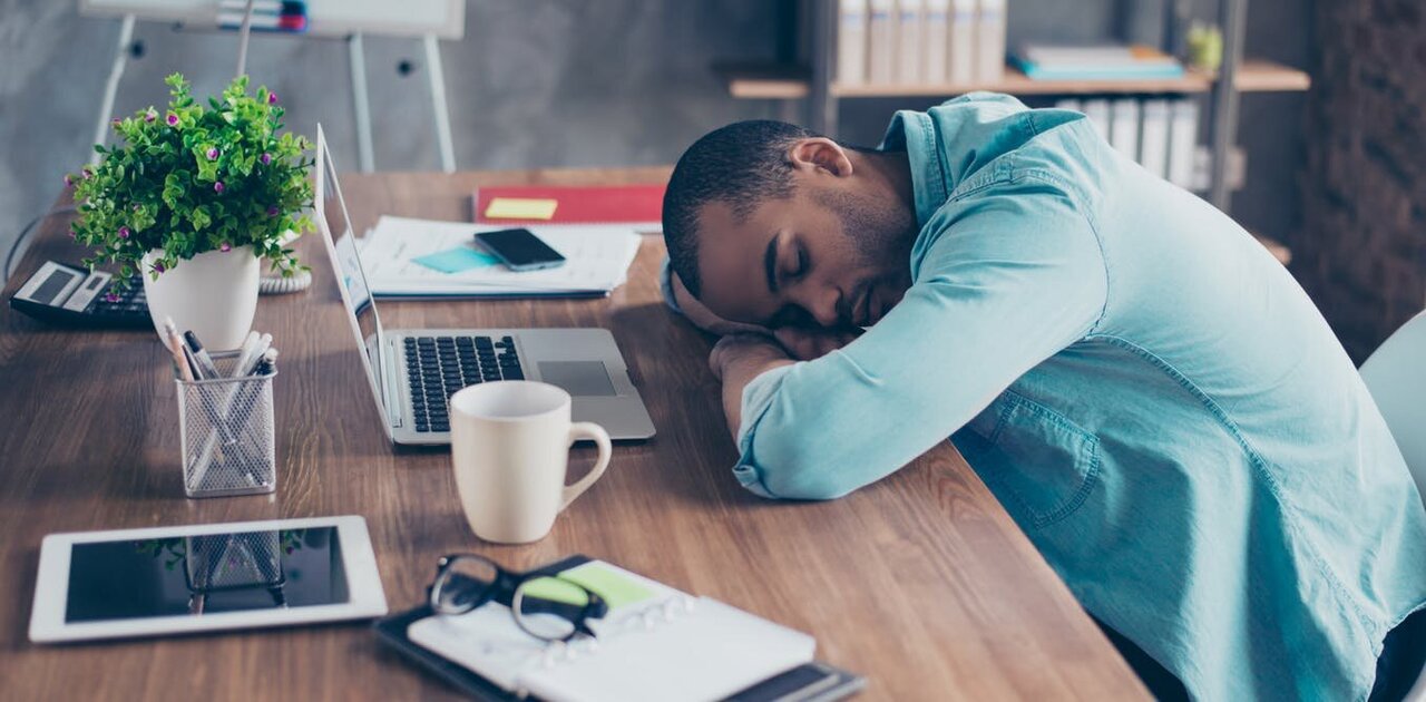 Pekerja wanita tidur atau mengantuk di meja kerja pejabat.